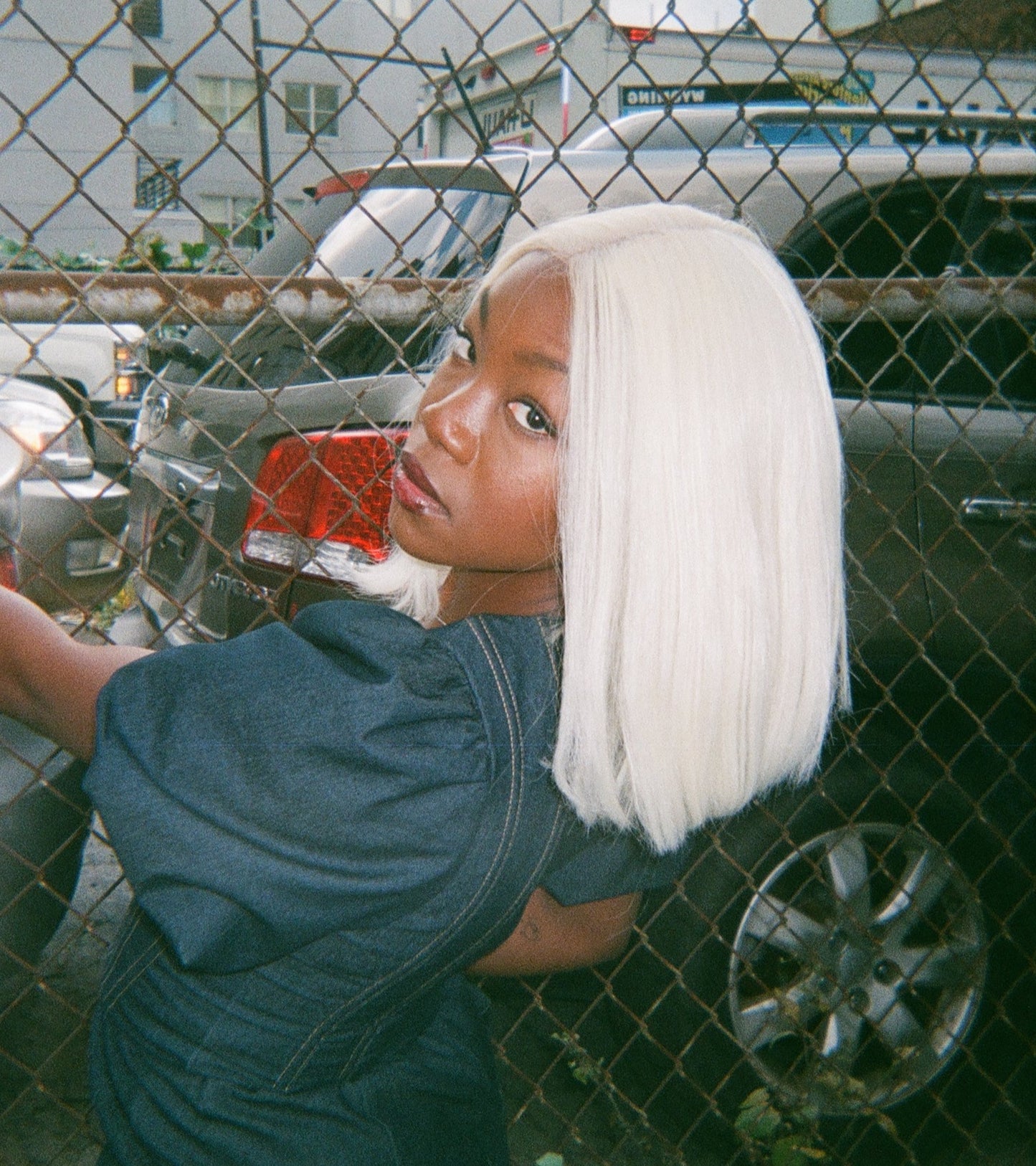 Woman with platinum blonde synthetic hair wig posing in front of a fence.